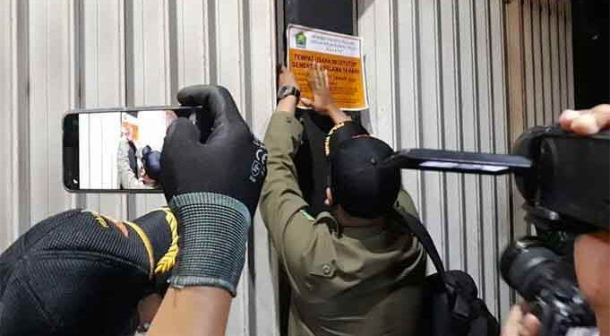 Petugas Satpol PP Kota Malang tengah melakukan penyegelan terhadap salah satu kafe akibat bandel tetap beroperasional di luar jam ketentuan PPKM, Jumat (15/1/2021). (Foto : Azmy).