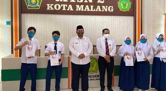 Sugiarto Kasmuri Kepala OJK Malang bersama para siswa yang menerima smarphone.(foto: dok/ojk).