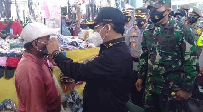 Wali Kota Malang, Sutiaji memakaikan masker pada salah seorang pedagang di Pasar Bunul.(foto: Humas Pemkot Malang).
