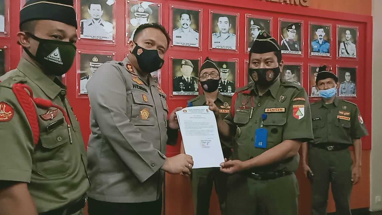 Wakil Kepala Banser Kabupaten Malang, M Mukhlis Mubarak menyerahkan dokumen laporan ke Kapolres Malang, AKBP Hendri Umar.(foto: Rizal Adhi Pratama).