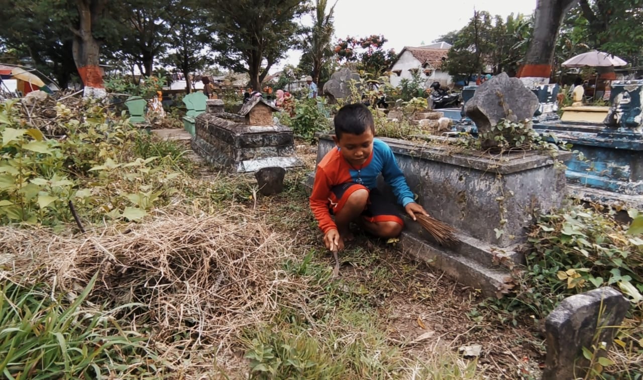 Dian Kurniawan (8), bocah pemburu rejeki di kuburan TPU Kutobedah, Kota Malang. Foto/Azmy