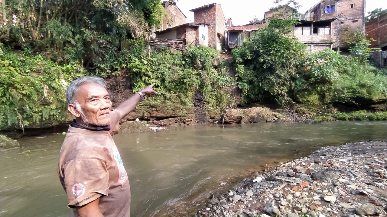 Misdi (68), seorang warga menunjukkan lokasi tanah bangunan toilet di bibir sungai Metro yang longsor, Sabtu (1/5/2021). Foto/Azmy