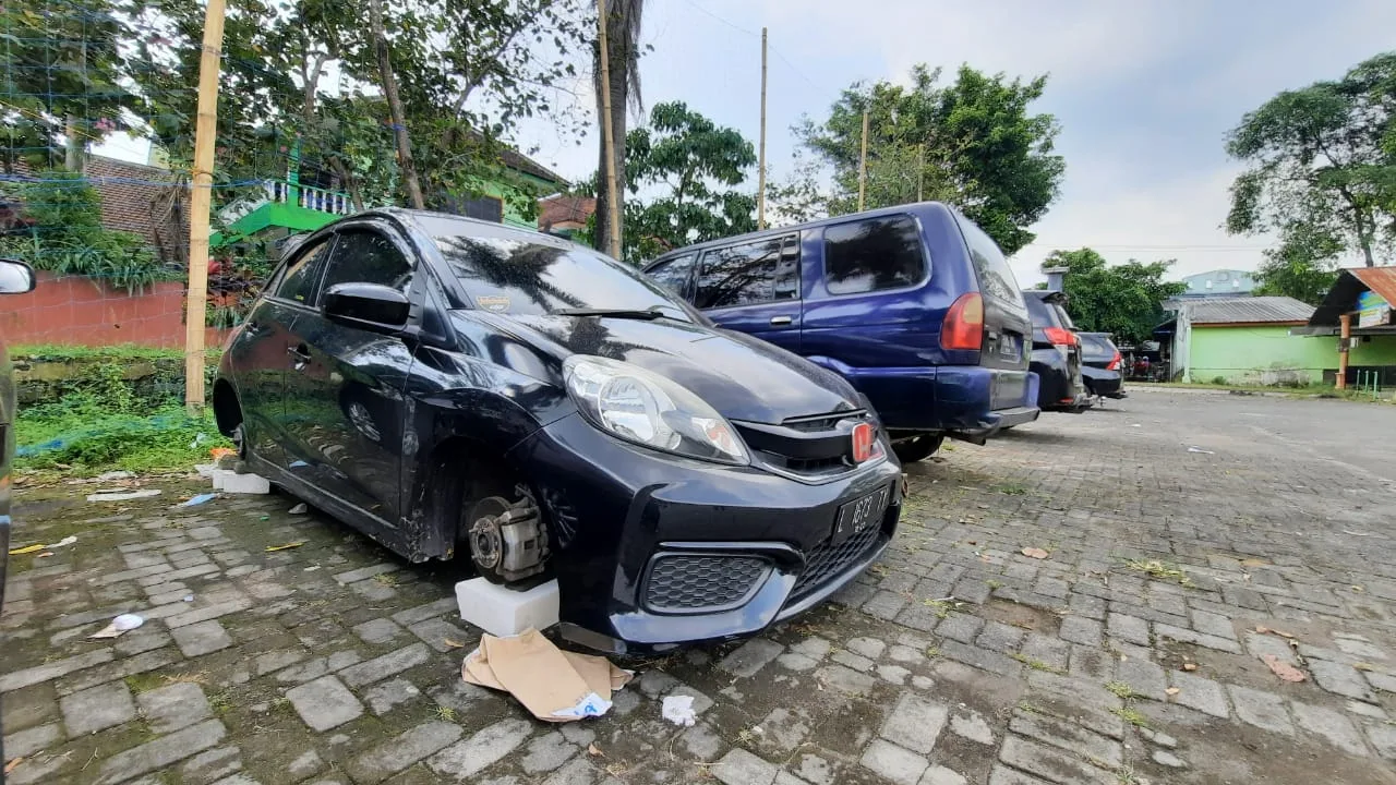 Kondisi 2 unit mobil yang terparkir di Lapangan Merjosari, Kota Malang yang sudah tanpa ban. Foto/Azmy.