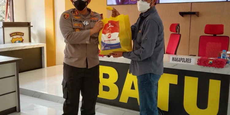 Kapolres Batu, AKBP Catur C Wibowo, saat memberikan bantuan sembako kepada masyarakat. Foto: M Sholeh
