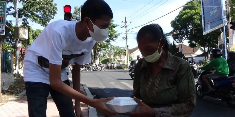 Andan membagikan nasi kotak pada pemakai jalan. dok