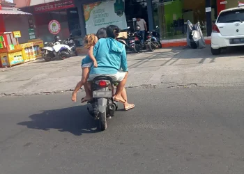 Pengendara sepeda motor di Jalan Ranu Grati, Kota Malang, Rabu siang (24/8). Sepeda motor tersebut dinaiki 4 orang. Dua orang dewasa, yang tampaknya pasangan suami istri/ tugu malang