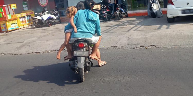 Pengendara sepeda motor di Jalan Ranu Grati, Kota Malang, Rabu siang (24/8). Sepeda motor tersebut dinaiki 4 orang. Dua orang dewasa, yang tampaknya pasangan suami istri/ tugu malang