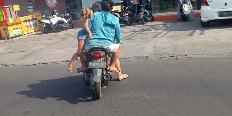 Pengendara sepeda motor di Jalan Ranu Grati, Kota Malang, Rabu siang (24/8). Sepeda motor tersebut dinaiki 4 orang. Dua orang dewasa, yang tampaknya pasangan suami istri/ tugu malang