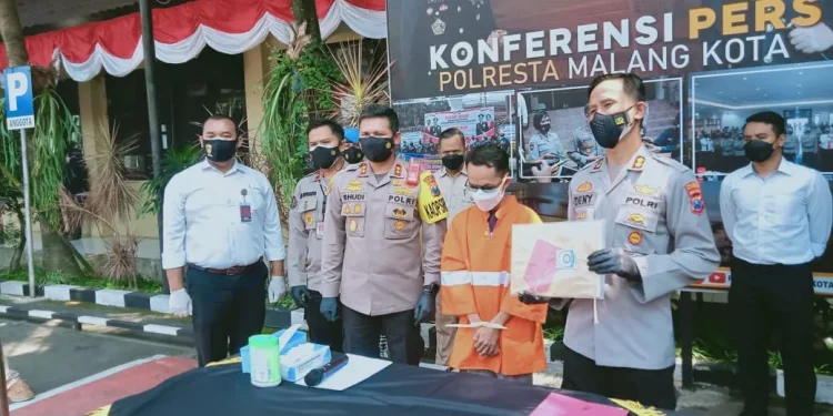 Tersangka yang asal kota Malang tertunduk saat rilis kasusnya di Mapolresta Malang Kota.