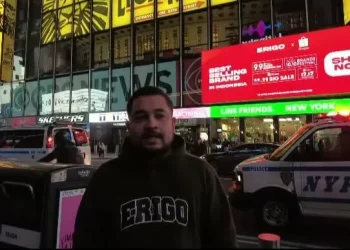 Muhammad Sadad saat berada di acara New York Fashion Week, di belakangnya tampak billboad Times Square New York di mana merek Erigo Store terpasang dengan slide warna merah/tugu malang
