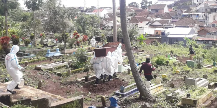 Tim pemulasaraan jenazah COVID-19 melakukan proses pemakaman. Foto: M Sholeh