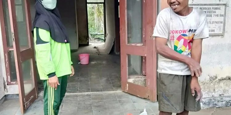 Murwati Handayani, relawan ODGJ, ketika menyambangi Bambang, ODGJ yang tinggal di gedung tua di depan SMAN Punung Kabupaten Pacitan. (Foto: Risma Wigati/Tugu Malang)