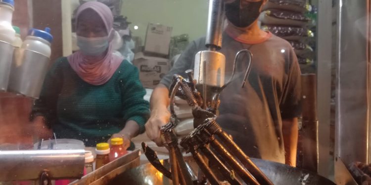 Dartadi dengan lengan kirinya yang patah memasak nasi goreng dengan mesin pengaduk nasi hasil inovasinya. Foto: M Sholeh