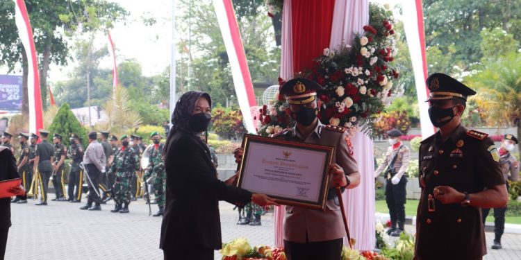 Kapolres Batu, AKBP I Nyoman Yogi Hermawan saat menerima penghargaan dari Wali Kota Batu, Dewanti Rumpoko atas peran aktifnya dalam percepatan vaksinasi COVID-19. Foto: Polres Batu