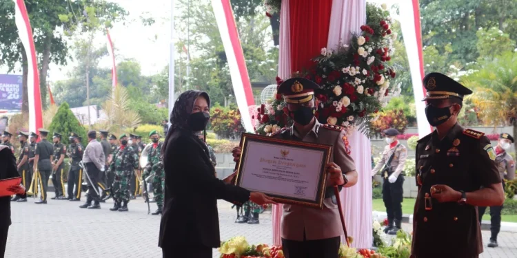 Kapolres Batu, AKBP I Nyoman Yogi Hermawan saat menerima penghargaan dari Wali Kota Batu, Dewanti Rumpoko atas peran aktifnya dalam percepatan vaksinasi COVID-19. Foto: Polres Batu