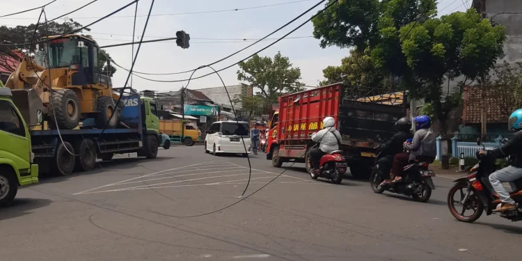 kabel melintang di atas jalan di Bululawang akibat diterjang truk pengangkut buldoser.