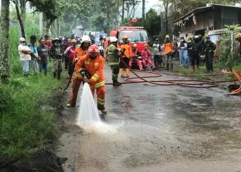 Petugas BPBD Kota Batu melakukan pembersihan lumpur di jalan Abdul Gani