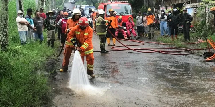 Petugas BPBD Kota Batu melakukan pembersihan lumpur di jalan Abdul Gani