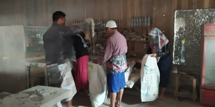 Nurul Hasanah (29) tengah mengemasi dagangan di warungnya pasca terjangan awan panas guguran yang merobohkan Jembaran Gladak Perak, pada Minggu (5/12/2021). Foto: Ulul Azmy