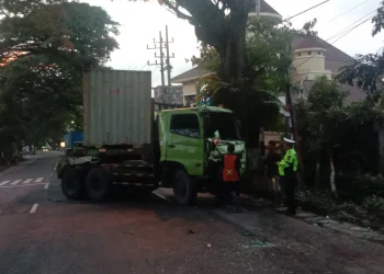 Tak Kuat Menanjak, Truk Kontainer Mundur dan Tabrak Pagar Rumah Warga Junrejo