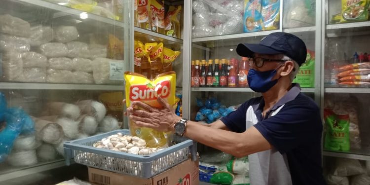 Nur Yakin, pedagang sembako dan minyak goreng di Pasar Besar Kota Malang menunjukkan dagangannya. Foto: M Sholeh