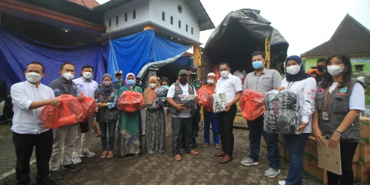 Dari kiri: Ketua Perbarindo Malang, Khoirul Anam; Ketua AAUI Malang, Hariyanto; Ketua APPI Malang, Suryadi; perwakilan warga dan relawan; Kepala OJK Malang, Sugiarto Kasmuri; CEO Tugu Media Group, Irham Thoriq; Wakil Kepala Cabang Bank Jatim Malang, Asri saat menyerahkan bantuan langsung ke posko Balai Desa Penanggal. Foto: Loah Mahfud