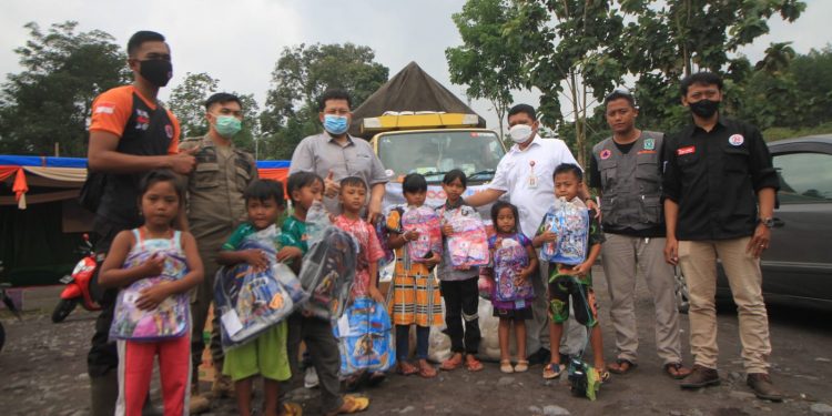 Rombongan OJK Malang bersama Tugu Media Group membagikan bantuan tas sekolah untuk anak-anak pengungsi di Desa Penanggal, Lumajang. Foto: Loah Mahfud
