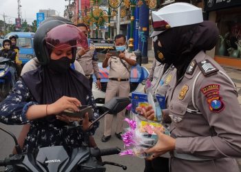 Anggota Polresta Malang Kota membagikan cokelat kepada pengendara di Kota Malang. Foto: Polresta Malang Kota