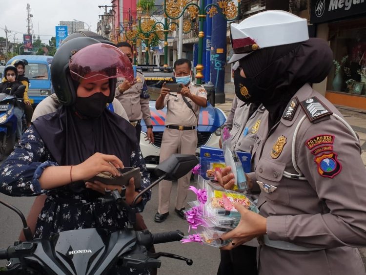 Anggota Polresta Malang Kota membagikan cokelat kepada pengendara di Kota Malang. Foto: Polresta Malang Kota