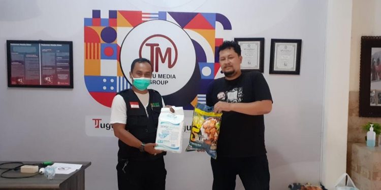 Ruwiyanto (kiri) dari BMH menyerahkan donasi secara simbolis di kantor Tugu Media Group. Foto : dok