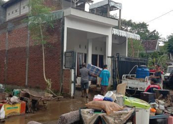 Ridho Siswantono, korban luapan Sungai Kali Sari Kota Malang (mengangkat kasur) membersihkan rumahnya. Foto: M Sholeh