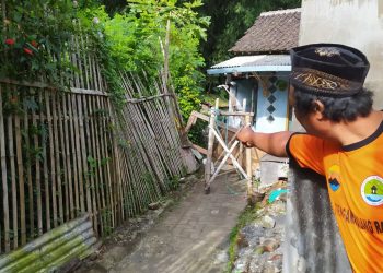 Seorang warga menunjukkan lokasi tebing yang longsor di belakang rumah warga, di Jalan Pattimura Gang V RT 5 RW 6, Kelurahan Temas, Kota Batu. 4 rumah warga berada di ambang bahaya. Foto: Ulul Azmy