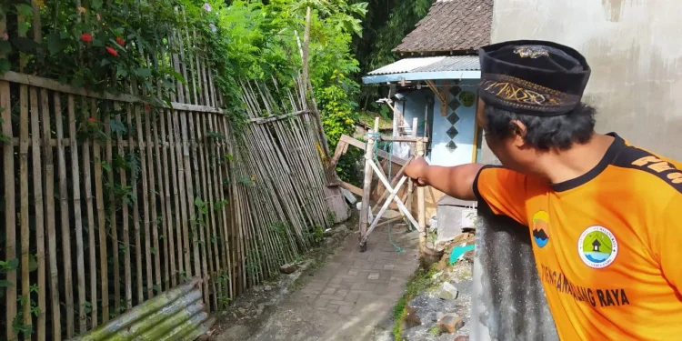 Seorang warga menunjukkan lokasi tebing yang longsor di belakang rumah warga, di Jalan Pattimura Gang V RT 5 RW 6, Kelurahan Temas, Kota Batu. 4 rumah warga berada di ambang bahaya. Foto: Ulul Azmy