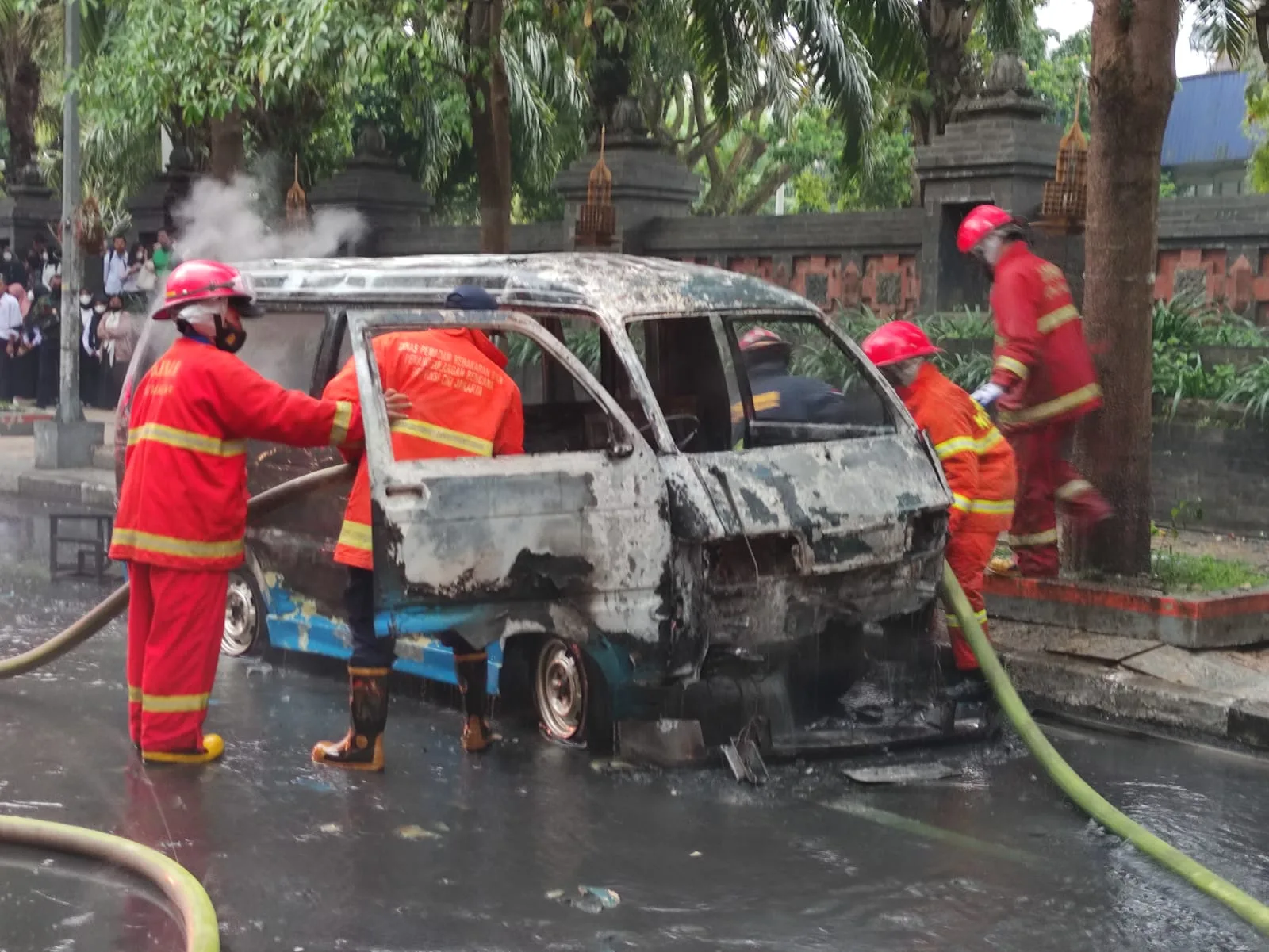 Petugas melakukan proses pemadaman kebakaran angkot di Jalan Veteran Kota Malang.