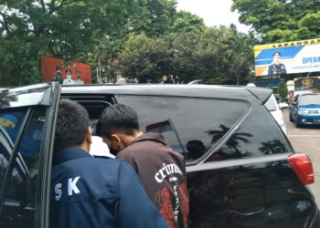 Pengunggah video (jaket coklat) usai memberikan keterangan di Polres Malang.