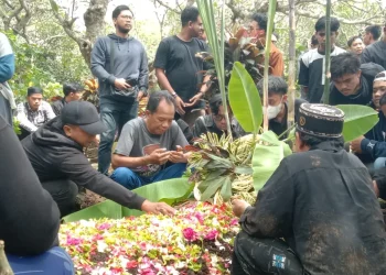 Kerabat dan pelayat berdoa di pusara korban Tragedi Kanjuruhan.