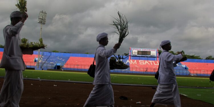 Umat Hindu memercikkan air di Stadion Kanjuruhan untuk membersihkan energi negatif. Foto/Rubianto