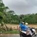 Warga melintas di tepi Sungai Panguluran yang debit airnya meninggi saat musim hujan.