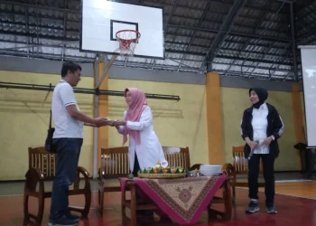 Kepala SMAN 8 Malang saat menyerahkan potongan tumpeng kepada kapten tim basket puteri.