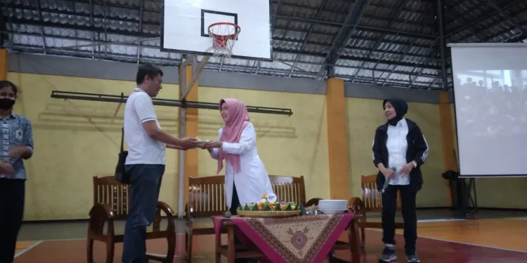 Kepala SMAN 8 Malang saat menyerahkan potongan tumpeng kepada kapten tim basket puteri.