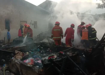 Petugas melakukan pemadaman sisa sisa api yang membakar rumah kontrakan di Kota Malang.