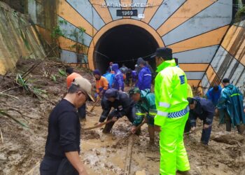 Petugas melalukan evakuasi material longsor di mulut terowongan kereta api di Karangkates.