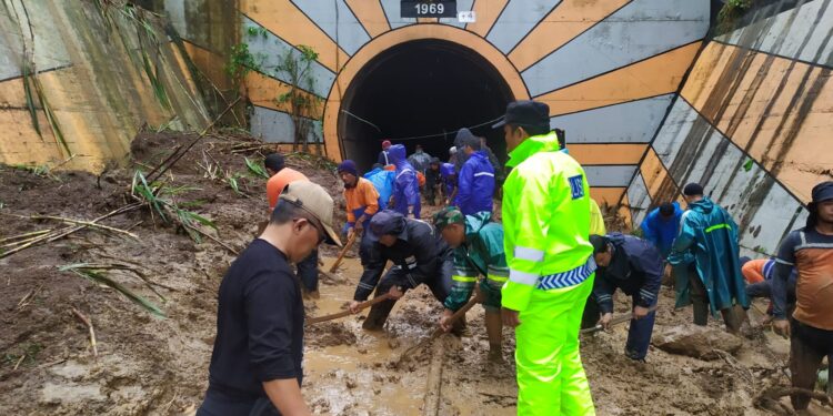 Petugas melalukan evakuasi material longsor di mulut terowongan kereta api di Karangkates.