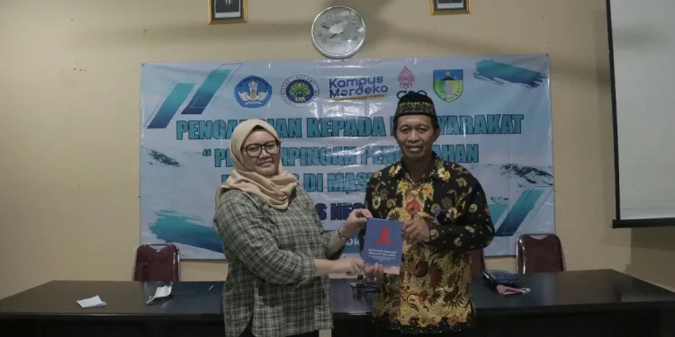 Dosen Pengabdian UM menyerahkan buku saku HIV AIDS. Foto dok. UM.