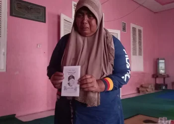 Winartiningsih memegang amplop dengan foto mendiang anaknya.