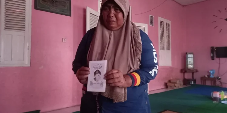 Winartiningsih memegang amplop dengan foto mendiang anaknya.