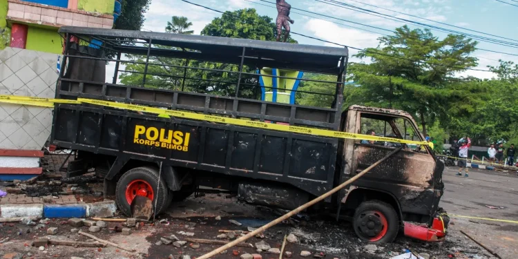 Kendaraan brimob yang dibakar oleh suporter Aremania.