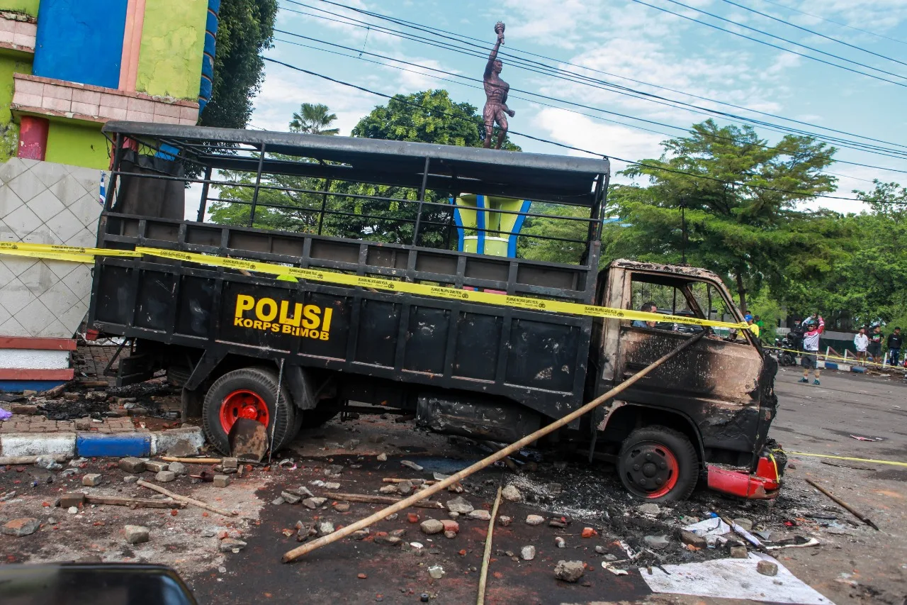 Kendaraan brimob yang dibakar oleh suporter Aremania.