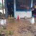 Warga dan relawan membersihkan sebuah warung yang dipenuhi lumpur akibat banjir.