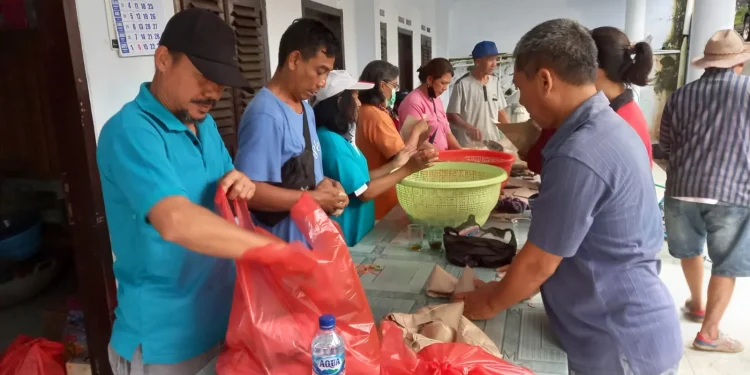 Para relawan dapur umum membungkus nasi untuk didistribusikan pada warga terdampak banjir di Sitiarjo.